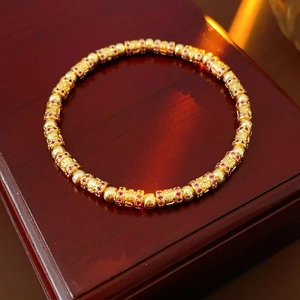 Macro shot of 18k gold plated cylinder bracelet with red zircons on wooden case