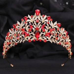 Elegant gold bridal crown with red crystals and leaf design on black velvet background