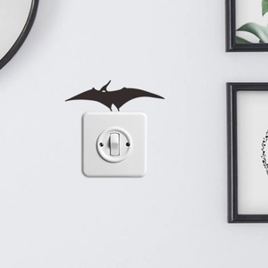 Detail of black pterosaur silhouette sticker on white circular light switch panel decoration
