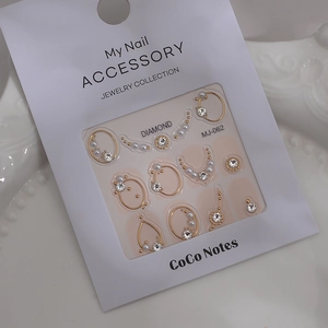 Macro shot of gold-rimmed nail art charms with rhinestones and pearls on MJ-062 card