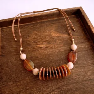 Bohemian double-layer necklace with faux pearls and amber resin beads on wooden tray