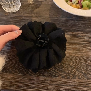 Detail of a large black lace flower hair claw clip with intricate fabric petal layers