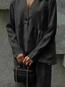 Detail of dark grey V-neck long sleeve top with button and pleated waist design