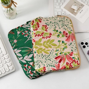 Macro view of floral embroidery detail and metal zipper on quilted laptop sleeves