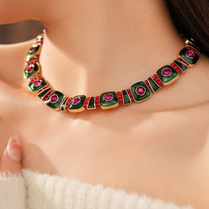 Detail of vintage enamel necklace featuring green squares and pink gems on model neck