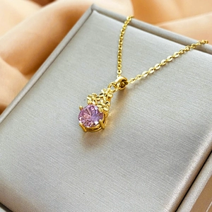 Dettaglio del ciondolo in zircone rosa con fiori dorati su seta champagne di lusso