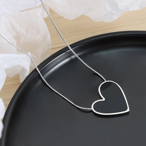 Dark style acrylic heart pendant necklace with silver chain on black ceramic plate