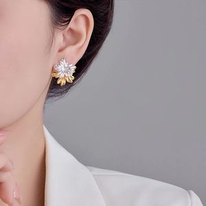 Two-tone floral stud earrings in gold and silver finish shown on a model's ear