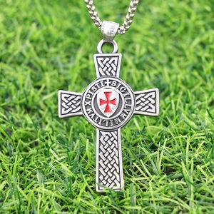 Detail of Maltese cross pendant with red shield and Latin engraving on green grass