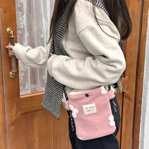 Detail of pink plush crossbody bag with 3D white flower and braided strap