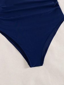 Detailed close-up of dark blue swimsuit leg opening with elastic edges and neat stitching