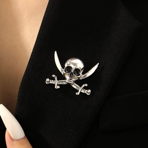 Detail of silver vintage pirate skull and cross swords brooch on black blazer lapel