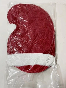 Détail d'un coussin en peluche en forme de bonnet de Noël emballé dans un sac plastique