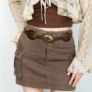 Detail of vintage brown belt with three circular metal rings on corduroy skirt
