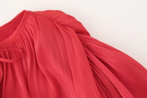 Dettaglio del mini abito rosso a pieghe con scollatura elegante e lacci decorativi