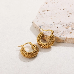 Macro detail of gold chunky hoop earrings featuring textured bubble bead pattern