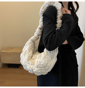 Detailed view of white pleated cloud bag with wave shoulder strap on a black coat