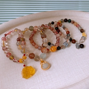 Macro detail of rutilated quartz lotus bracelets with agate and golden lucky charms