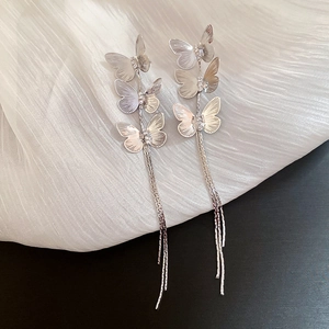 Detail of silver long tassel earrings with layered butterfly design on fabric