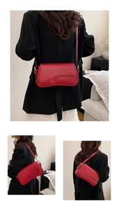 Detail view of red leather shoulder bag showing metal buckles and stylish crossbody strap