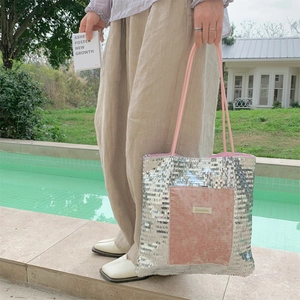 Detail of silver sequin tote bag featuring pink velvet pocket and brand logo