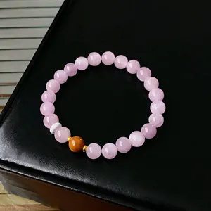 Elegant beaded bracelet with pink kunzite stones and golden accents on leather stand