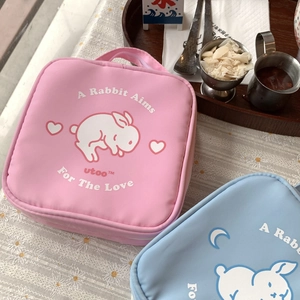 Detail of square makeup bags in pink and blue with cute rabbit print on lace tablecloth