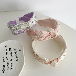 Close-up of floral embroidered knotted headbands in purple, pink, and beige mesh fabric