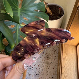 Macro detail of large acetate hair claw clip with dark purple tortoiseshell marble pattern