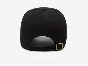 Detail of adjustable bronze metal buckle and cotton twill texture on black baseball cap