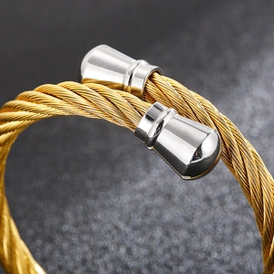 Macro detail of the twisted cable texture and silver cone tips on a gold C-shape bracelet