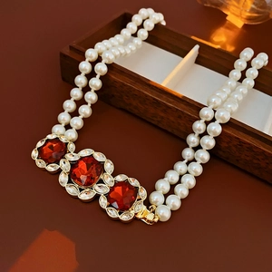 Close-up of vintage double-strand pearl necklace with red gemstones and gold plating