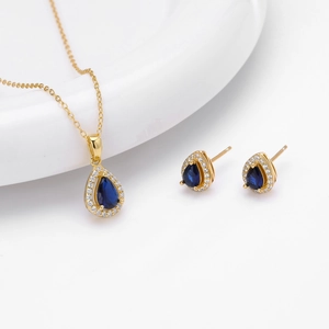 Close-up of golden necklace and earrings set with blue teardrop stones and zircons