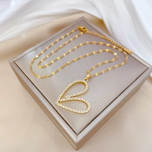 Luxurious gold heart pendant necklace with shimmering crystals on beige jewelry box