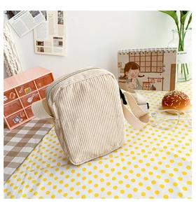 Detail of beige corduroy crossbody bag with adjustable strap in a cozy home setting