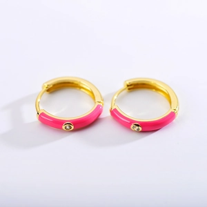 Detailed close-up of gold plated hoop earrings with pink enamel and sparkling zircon stone