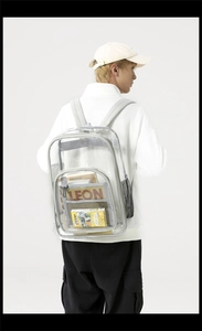 Rear view of a model wearing the clear waterproof PVC backpack with grey fabric straps