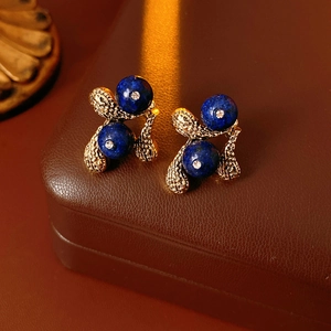 Detailed close-up of vintage gold floral earrings with deep blue lapis and small crystals