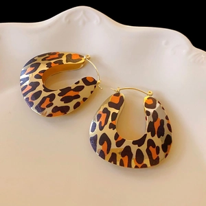 Macro detail of leopard print hoop earrings with gold plating on a white plate
