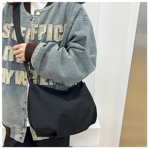 Model wearing a minimalist black nylon pleated dumpling bag with adjustable shoulder strap