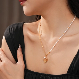 Gros plan détaillé d'un pendentif feuille d'érable dorée et collier de perles sur un mannequin