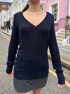 Close-up of navy blue V-neck knit sweater featuring classic thick cable patterns