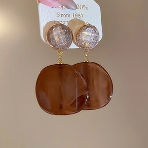 Detail view of retro brown resin hoop earrings with amber texture and gold connectors