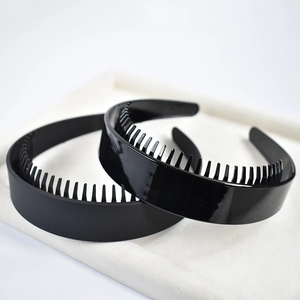 Close-up of glossy and matte black headbands with teeth for hair grip on a white cushion
