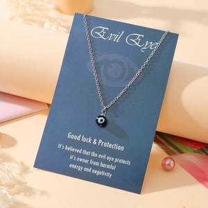Close-up of silver evil eye pendant necklace on a blue gift display card with dry flowers