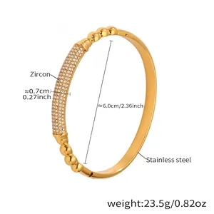 Dettaglio di un bracciale dorato in acciaio inossidabile con zirconi e perline lucide