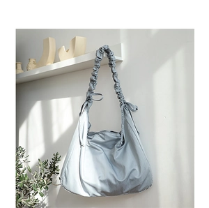 Detail of grey-blue nylon shoulder bag featuring a stylish ruched drawstring strap design