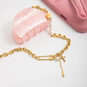 Détail du collier en acier doré 18K avec perles, croix et breloques en cœur luxe