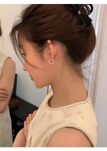 Detailed close-up of a white flower-shaped silver hoop earring worn by a model