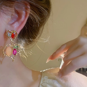 Detail of luxury heart earrings featuring colorful rhinestones and gold alloy setting